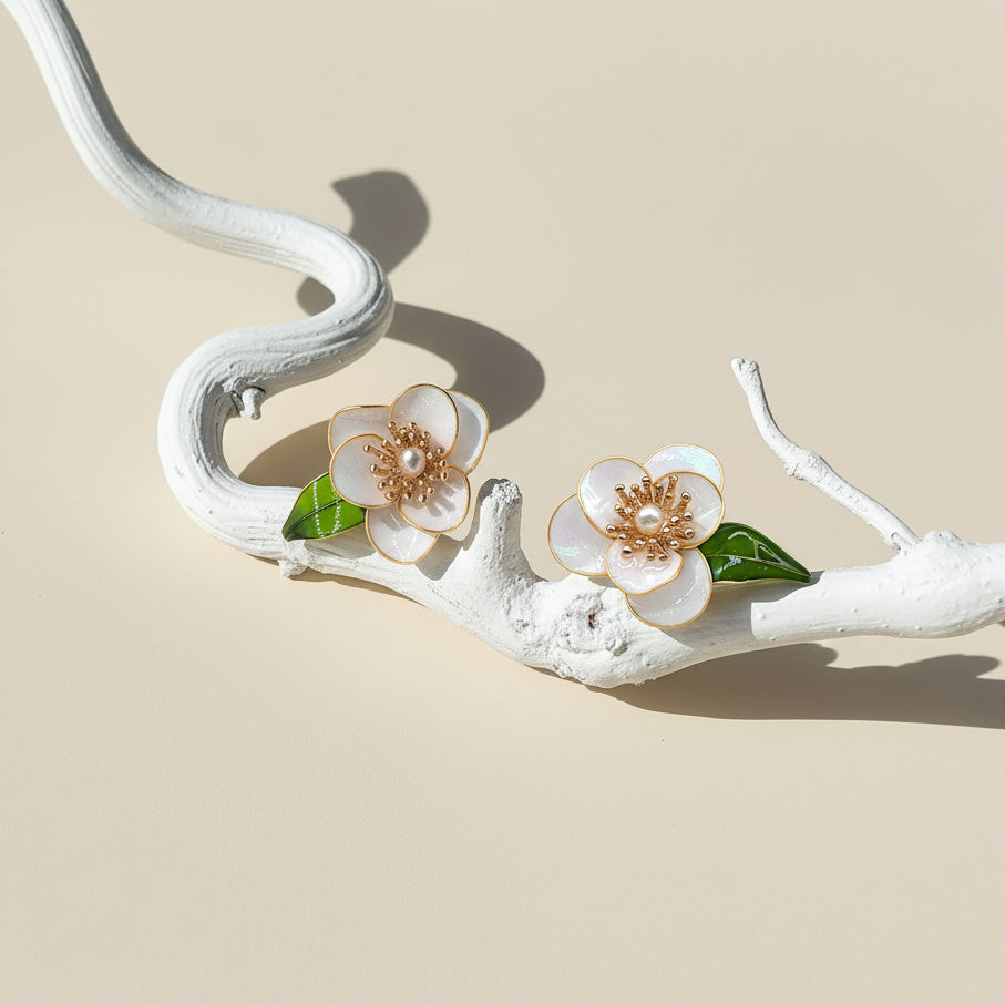 Floral earrings with pearls on a decorative branch against a beige background