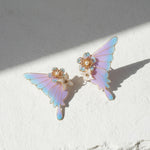 Butterfly-shaped earrings with pastel colors on a light background