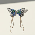 Butterfly-shaped earrings with floral details on a light background