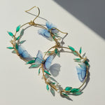 Earrings with blue butterfly and green leaf design on a light background