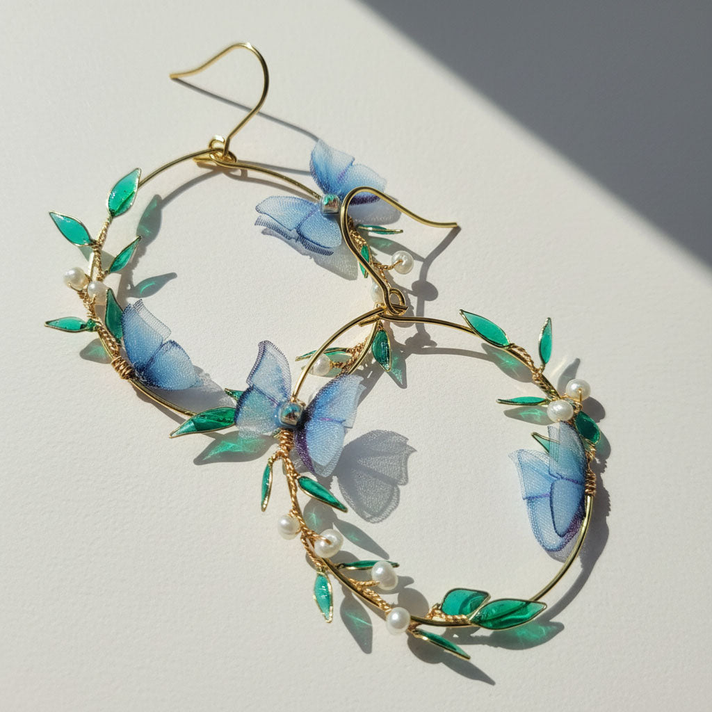 Earrings with blue butterfly and green leaf design on a light background