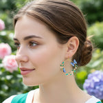 Woman wearing floral hoop earrings with a blurred garden background