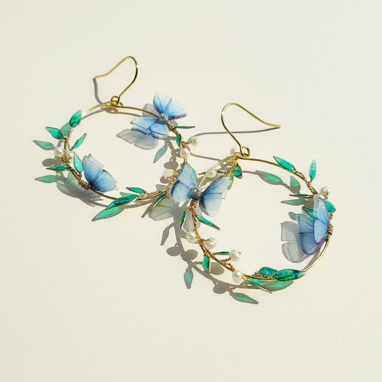 Earrings with butterfly and leaf design on a light background