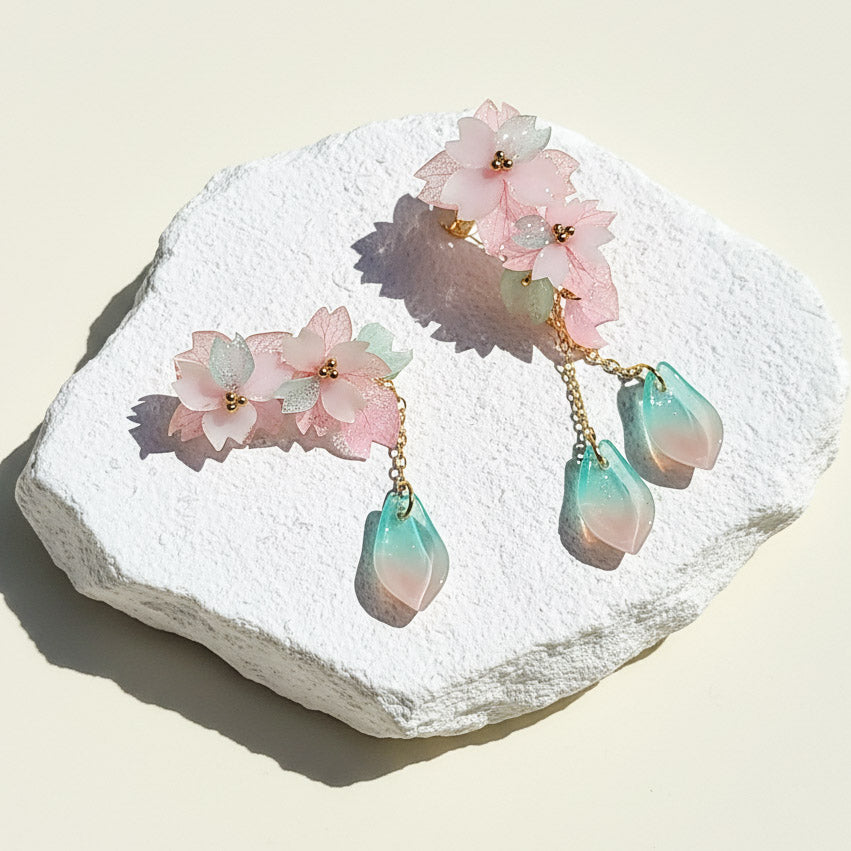 Pair of earrings with floral and teardrop designs on a textured white surface