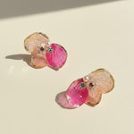 Pair of earrings with pink floral design on a beige background