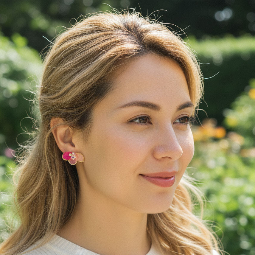 Woman wearing pink earrings with a blurred green background