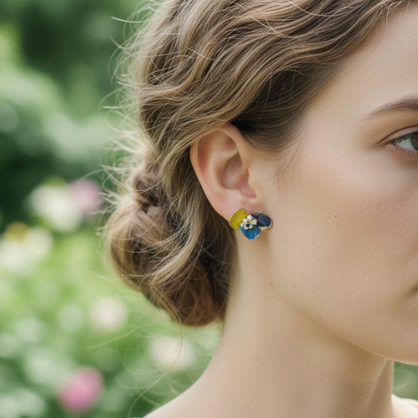 Close-up of a woman wearing floral earrings with a blurred garden background
