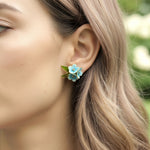 Close-up of a woman wearing a floral earring with a blurred natural background