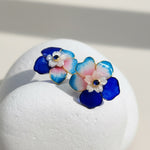 Colorful flower-shaped earrings on a white stone surface