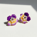 Pair of floral earrings with purple and yellow petals on a white background