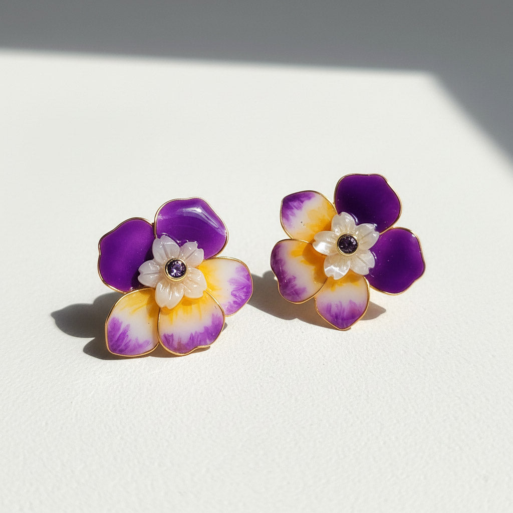 Pair of floral earrings with purple and yellow petals on a white background