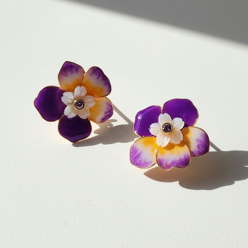 Flower-shaped earrings with purple, orange, and white colors on a light background