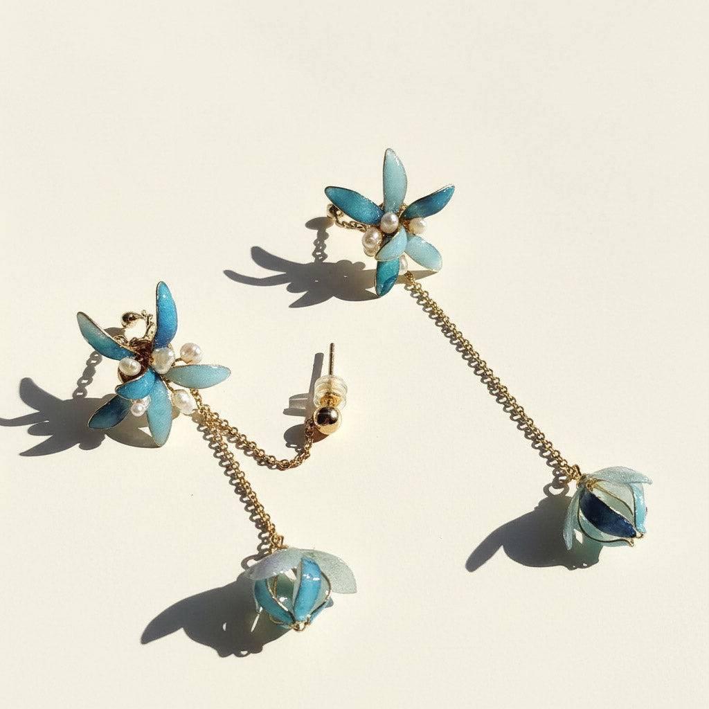 Pair of turquoise flower earrings with gold chains on a beige background