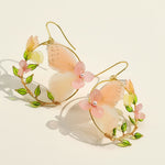 Pair of earrings with butterfly and floral design on a light background