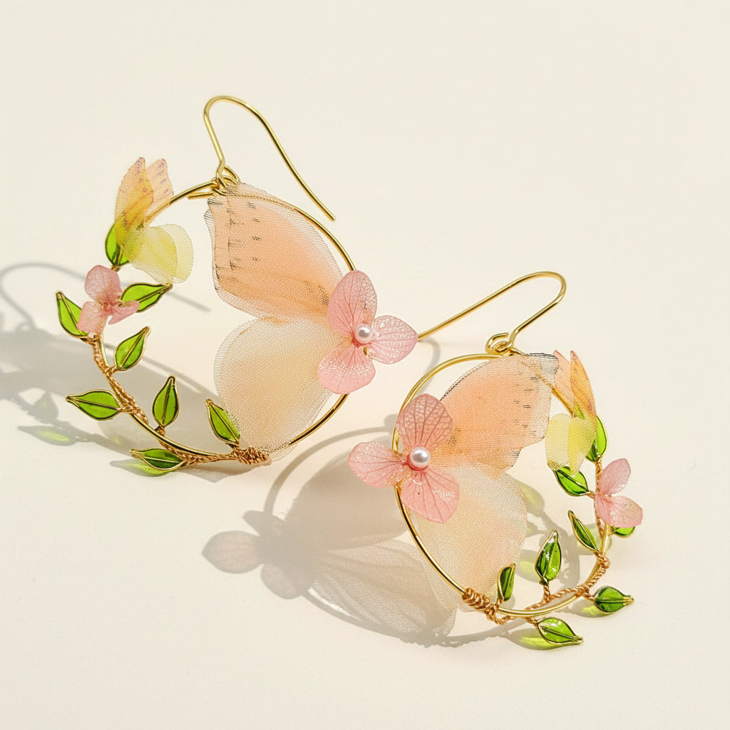 Pair of earrings with butterfly and floral design on a light background