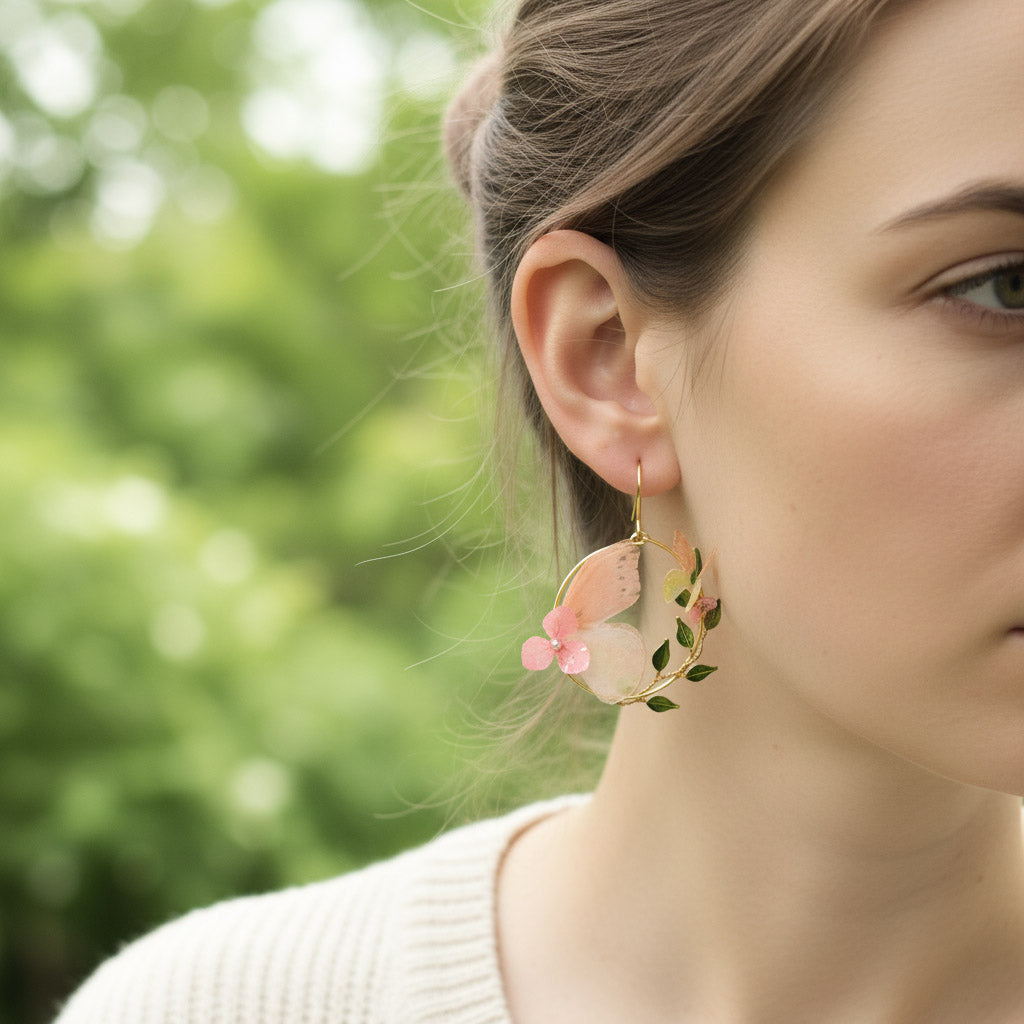 Close-up of a woman wearing floral earrings with a blurred green background