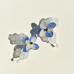 Pair of blue and white floral earrings on a light background