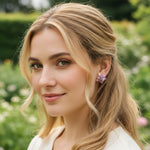 Woman with blonde hair and floral earrings in a garden setting