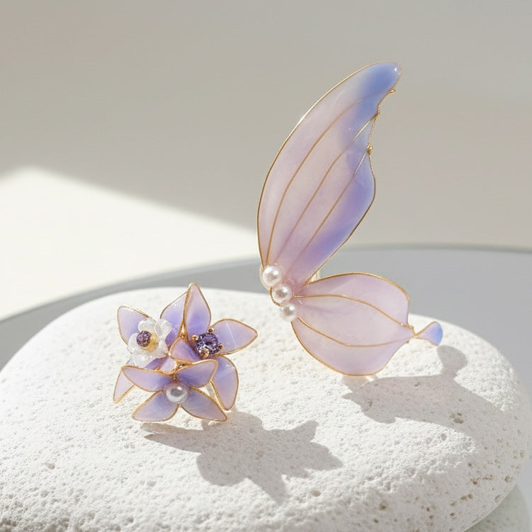 Butterfly and flower-shaped earrings with purple and gold accents on a light surface.