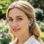 Woman wearing a decorative earring outdoors with a blurred natural background