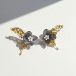Pair of floral hair clips with gold accents on a light background