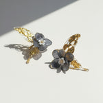 Pair of floral earrings with gold butterfly wings on a light background