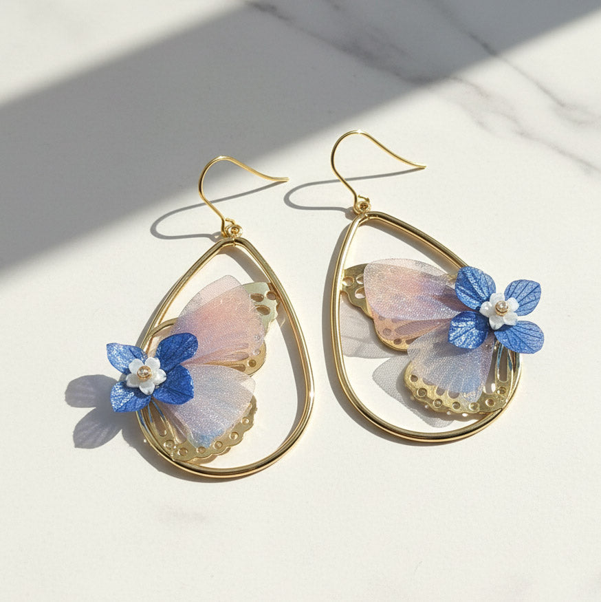 Gold earrings with butterfly-shaped flowers on a light background