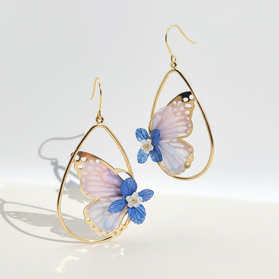 Butterfly-shaped earrings with gold frames on a light background