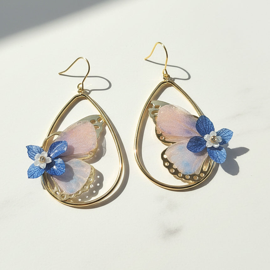 Gold earrings with butterfly-shaped flowers on a light background