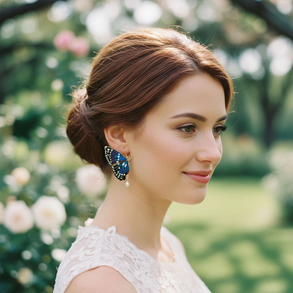 Woman wearing a blue butterfly earring outdoors with greenery in the background