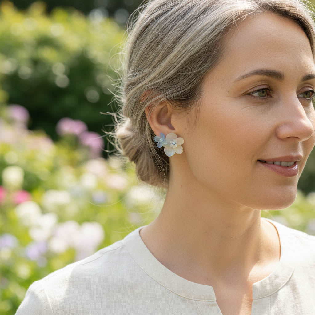 Woman wearing floral earrings with a blurred garden background