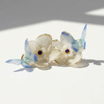 Decorative earrings with floral design and blue accents on a white background