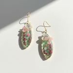 Pressed flower teardrop resin earrings with pink and purple blooms on gold-plated hooks.