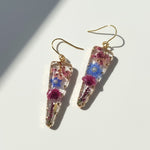 Trapezoid-shaped earrings with floral elements on a light background