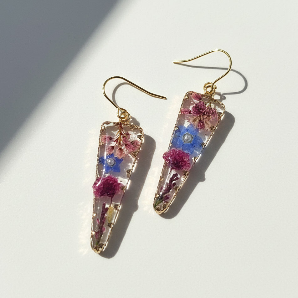 Trapezoid-shaped earrings with floral elements on a light background