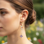Close-up of a woman wearing floral earrings with a blurred natural background