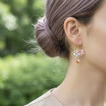 Close-up of a colorful earring worn by a person with a blurred green background