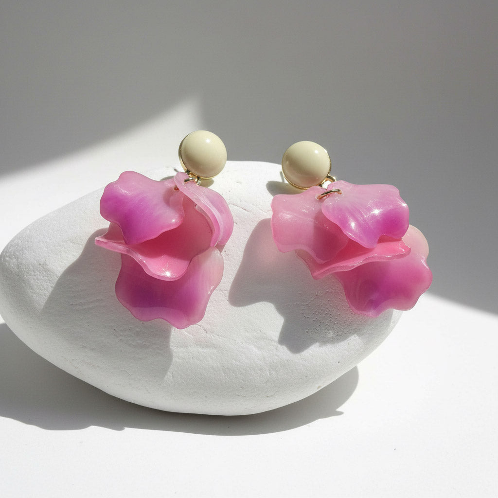 Pink floral earrings with beige centers on a white dish.