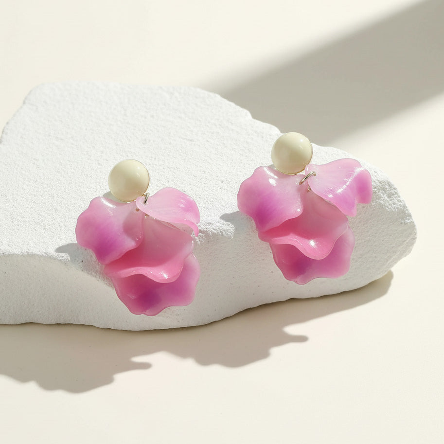 Pink flower-shaped earrings on a white stone surface