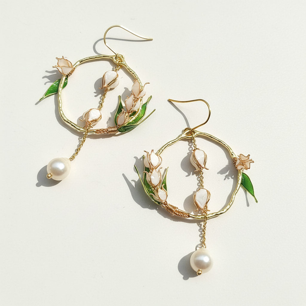 Pair of gold hoop earrings with pearl and floral details on a light background