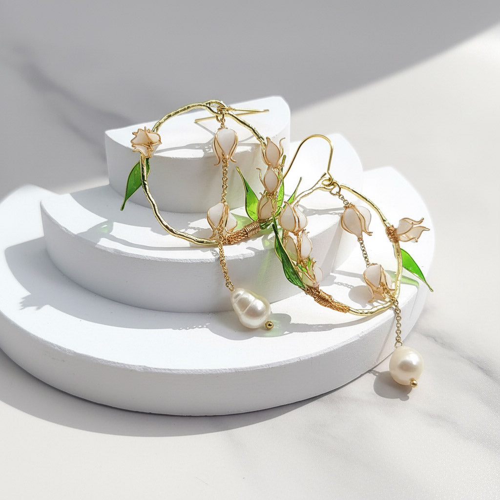 Gold and pearl earrings on a white pedestal with a soft background