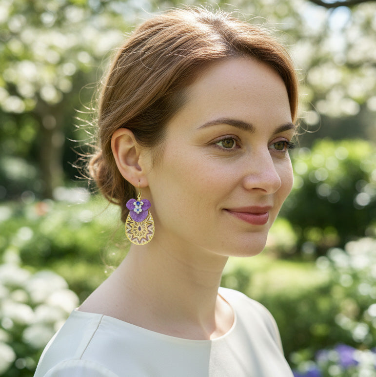 Woman wearing a floral earring outdoors with greenery in the background