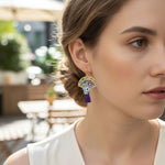 Woman wearing colorful earrings with a blurred outdoor background