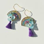 Colorful earrings with floral designs and tassels on a light background