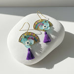 Colorful earrings with tassels on a white stone surface