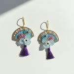 Decorative earrings with floral elements and tassels on a white background