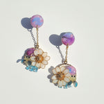 Pair of earrings with floral and insect designs on a light background