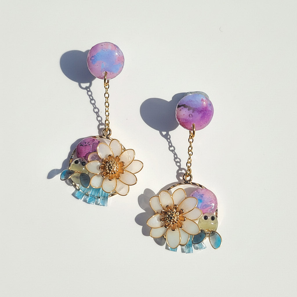 Pair of earrings with floral and insect designs on a light background
