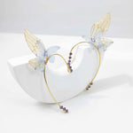 Delicate gold butterfly ear cuffs with translucent blue wings and purple crystal accents displayed on white stand.