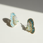 Pair of earrings with blue and gold design on a light background